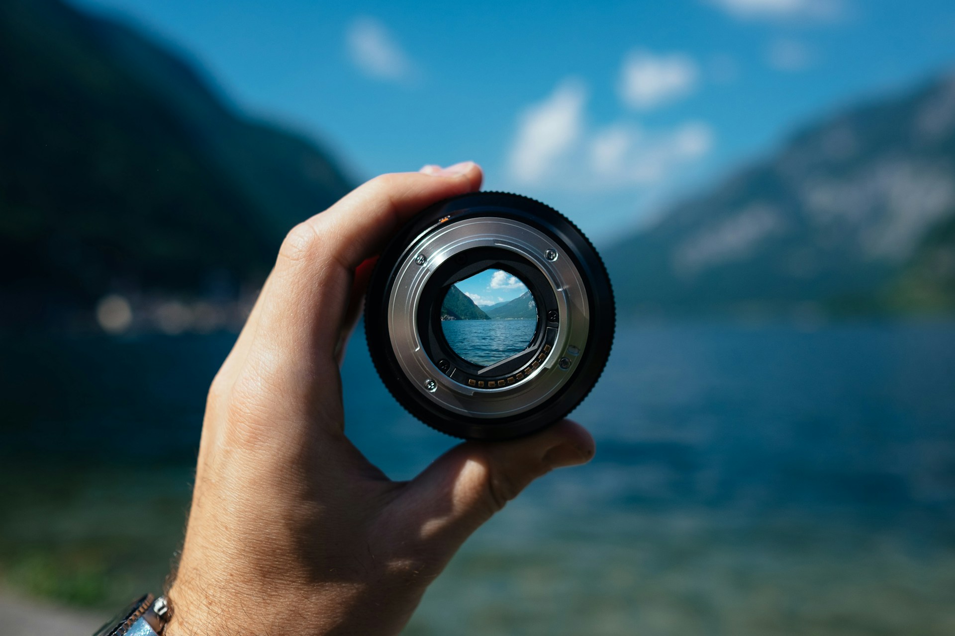 A camera lens held up in front of a lake