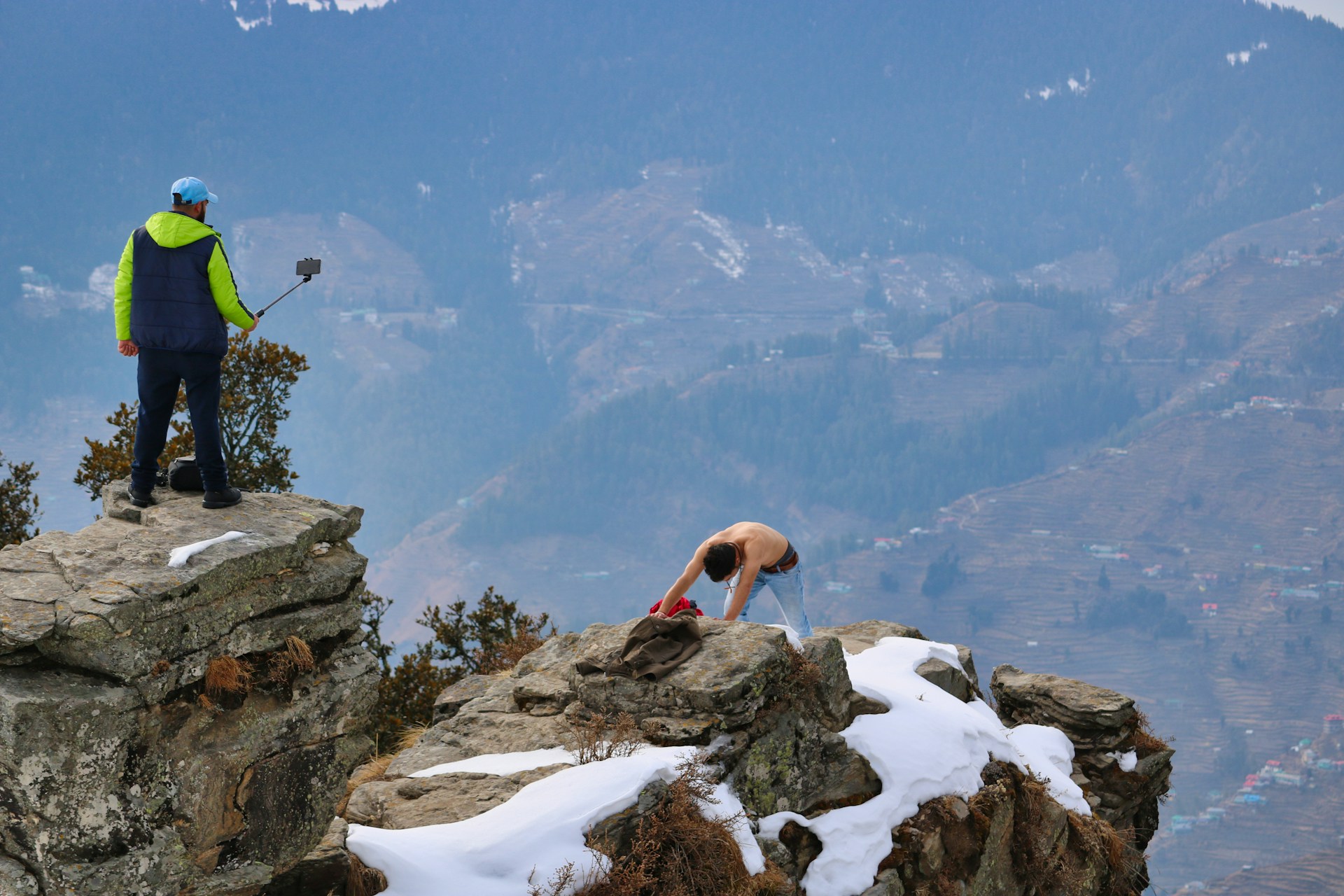 Two men with a selfie stick on a snowy clifftop