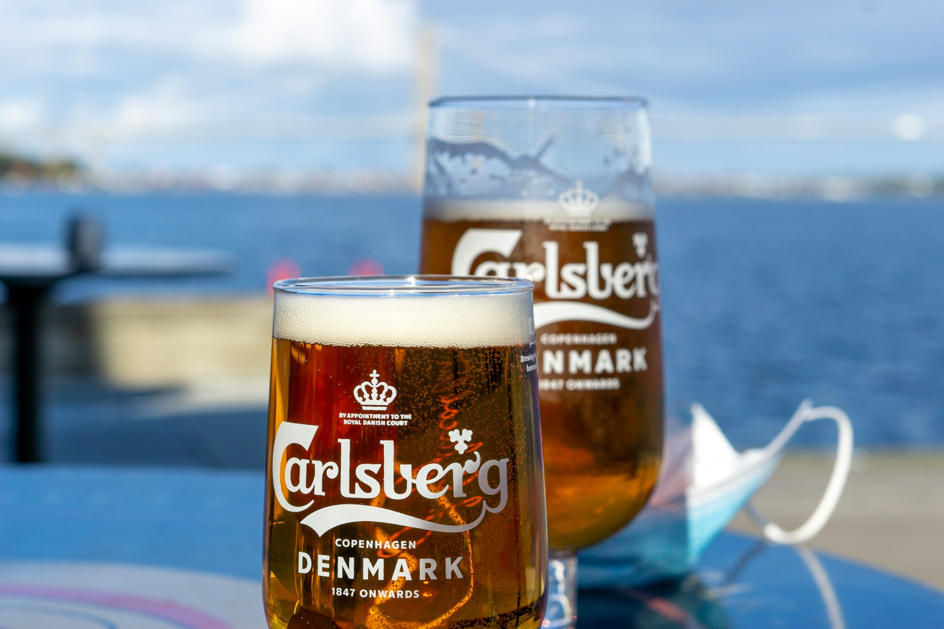 Two pints of Carlsberg against a coastal backdrop