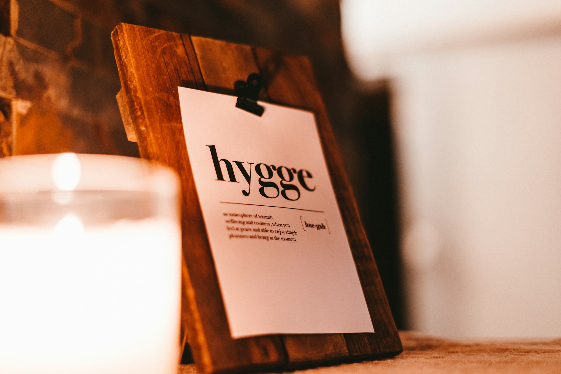 A candle and a sign that reads 'hygge' on a wooden board