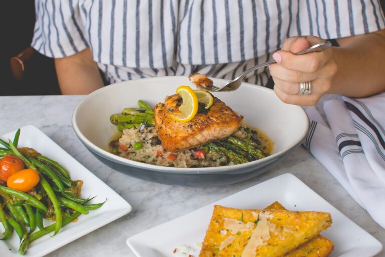 person eating fish with rice and vegetables