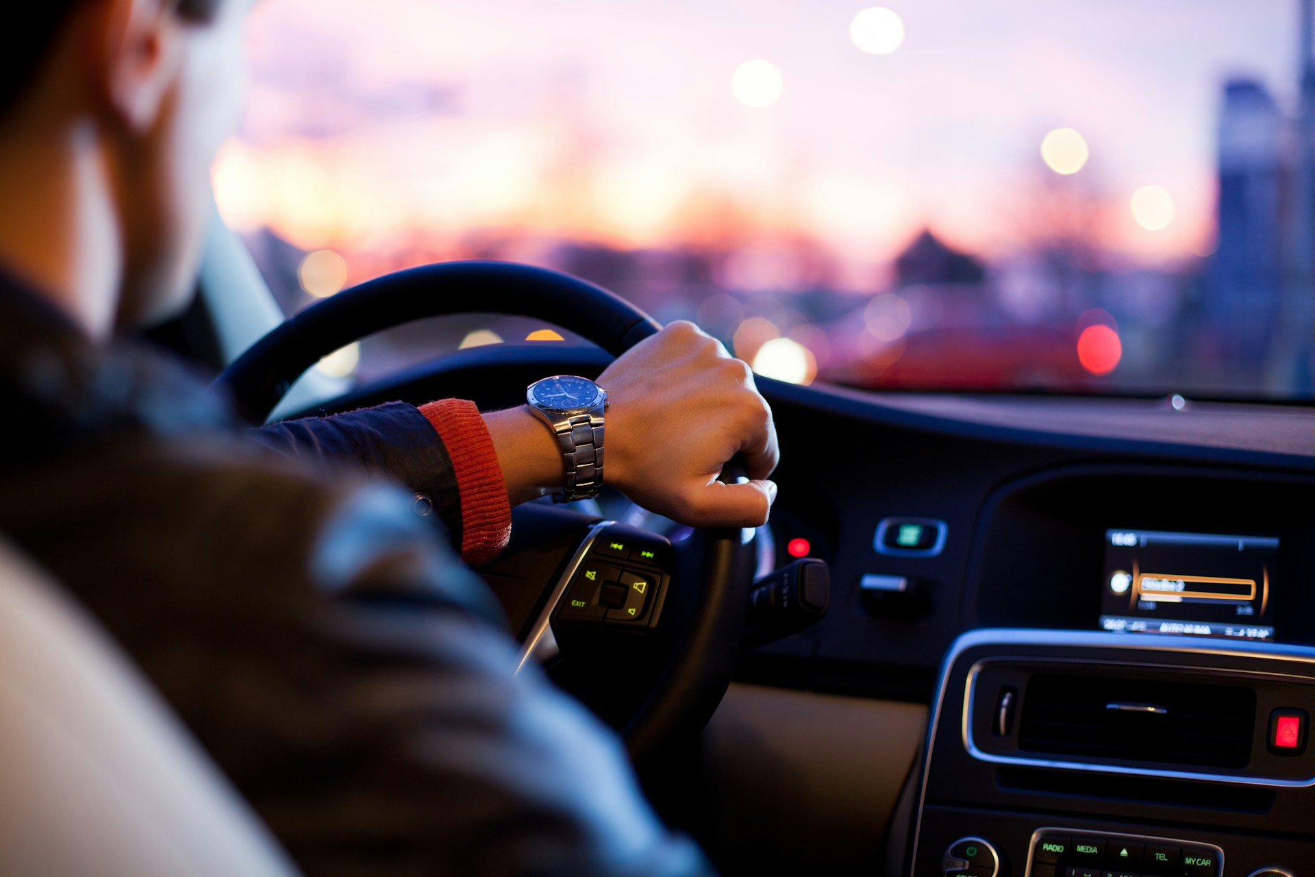 A man driving with one hand on the steering wheel