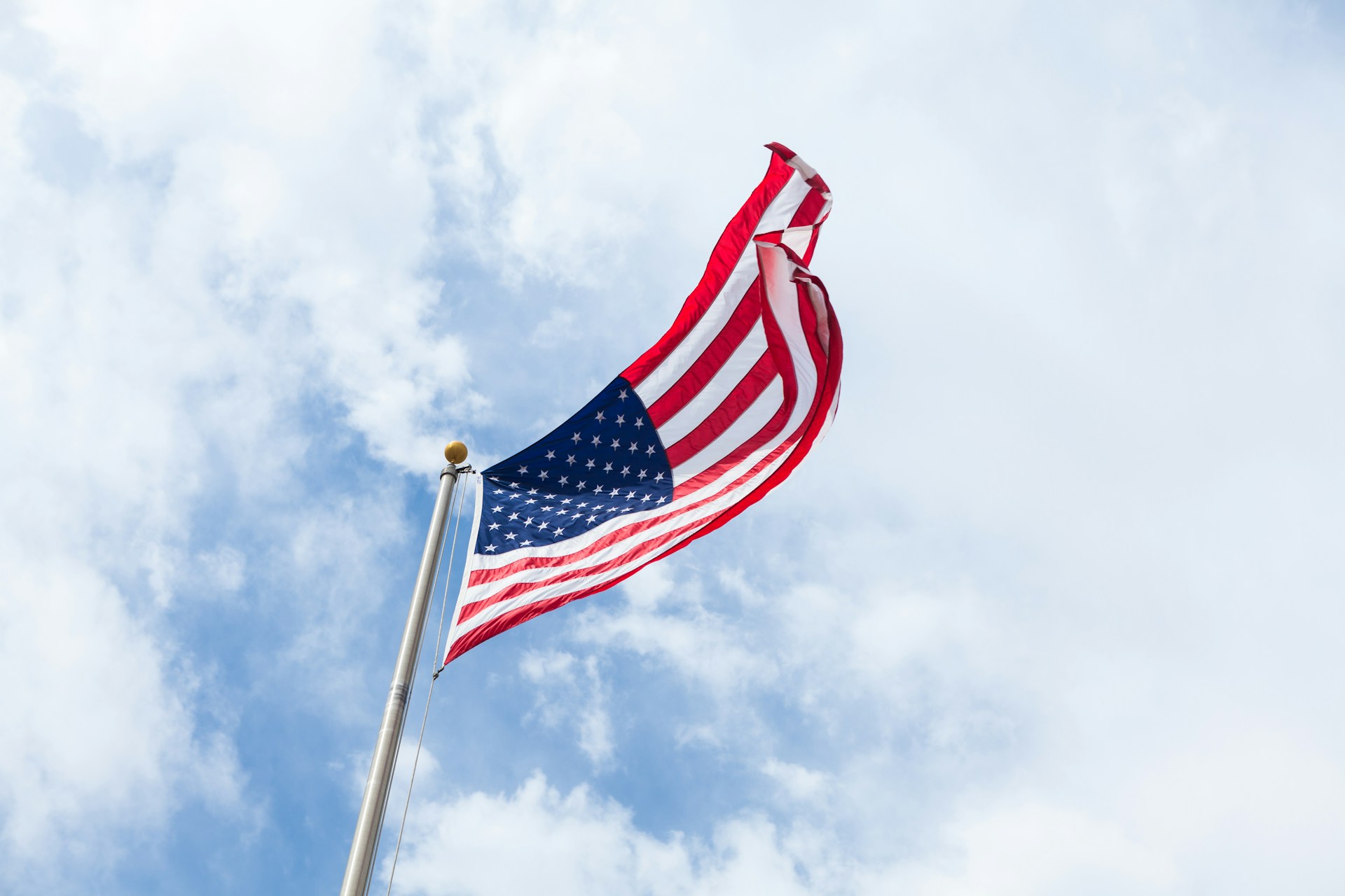 An American flay waving overhead, against a blue sky