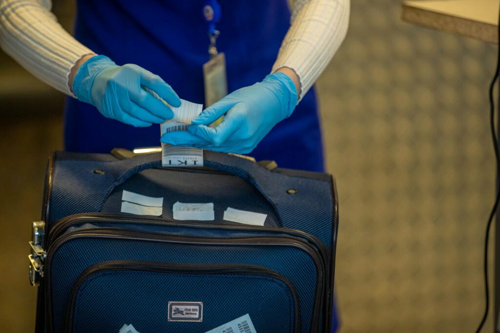 TSA agent with gloves, handling baggage tags.