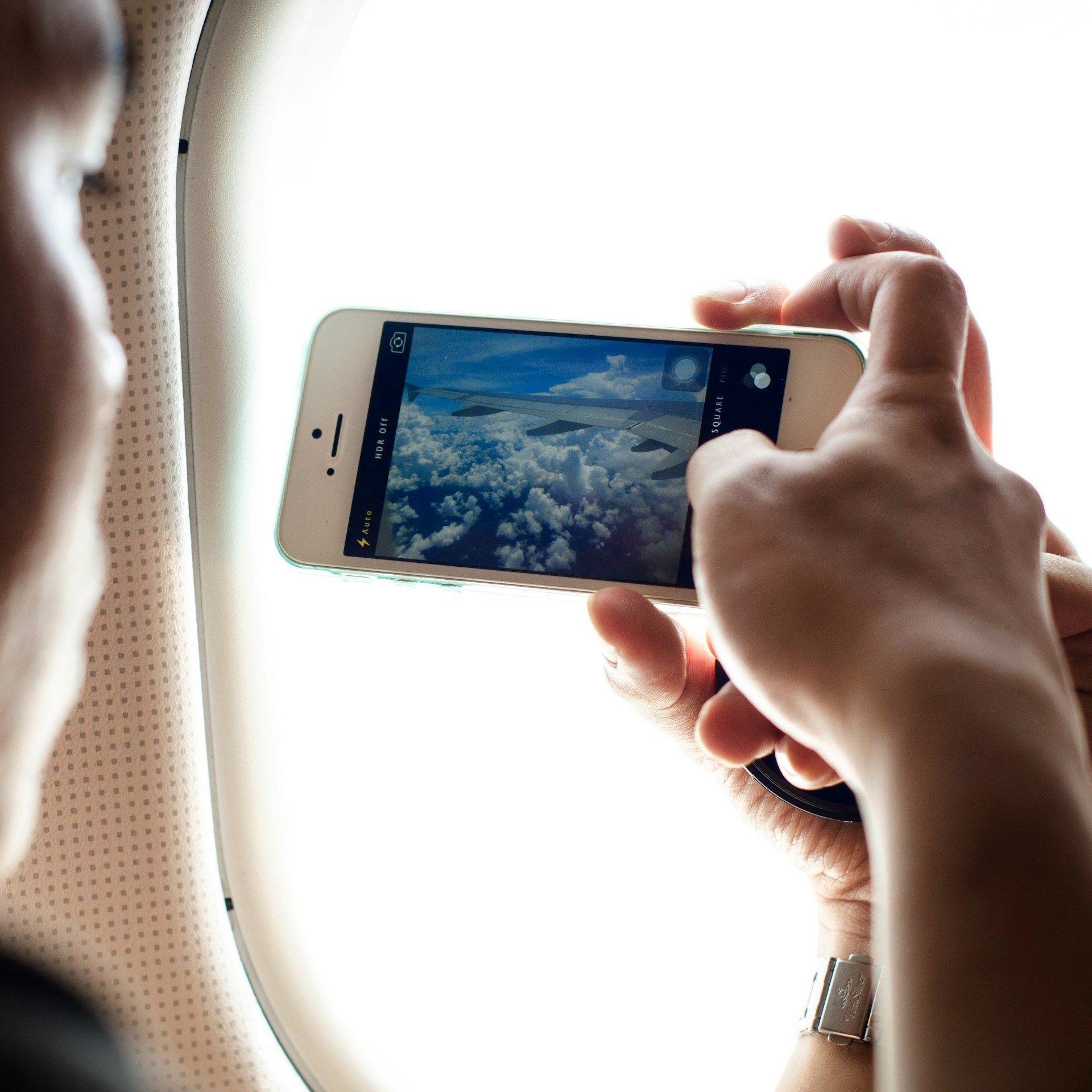 person taking photo on cell phone on airplane
